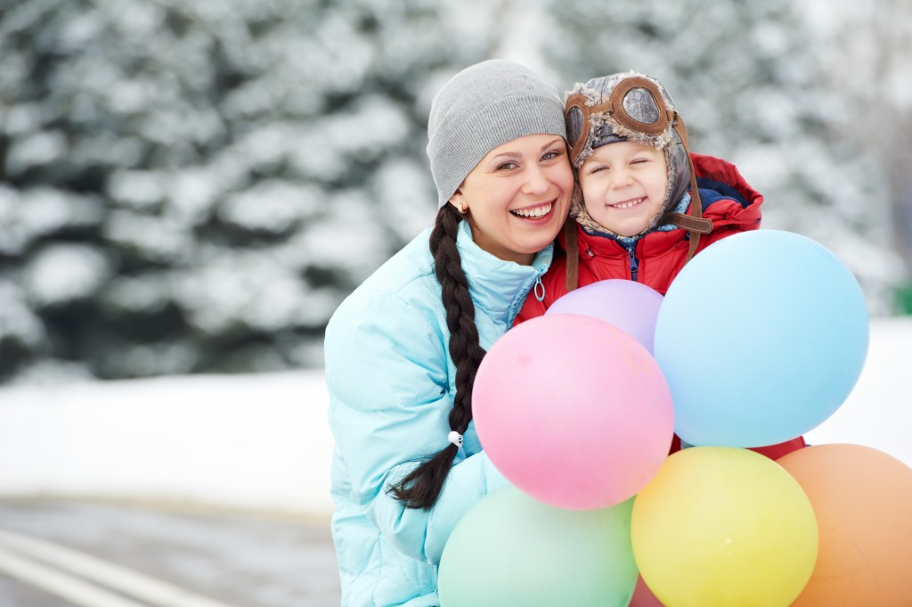 Portrait of happy mother with little child son boy and in winter outdoors
